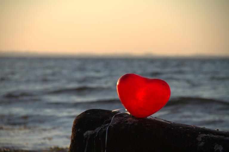 Et rødt hjerte på klippe foran havet