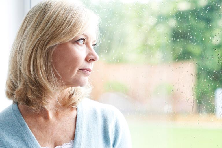 En kvinde ser ud af vindue med regndråber på